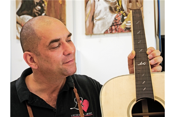 Roberto Fontanot mostra una chitarra a cui sta lavorando presso la sua nuova sede a Montelupone
